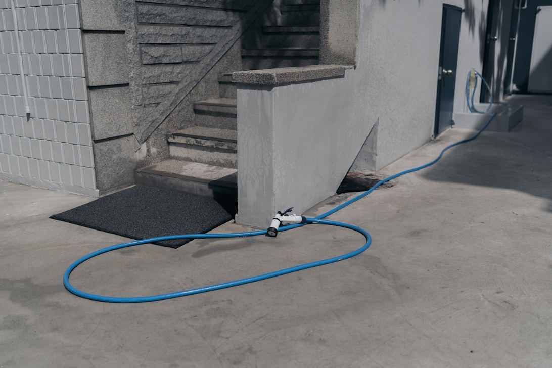Professionell testutrustning med blå slangar och övervakningsenhet placerad i ett källarutrymme, vilket visar en typisk installation för radonsanering.